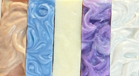 Stack of marbled soap bars in purple, white, and blue on a light gray background