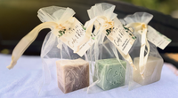 Three wedding soap bars in clear packaging with ribbons on a white surface.